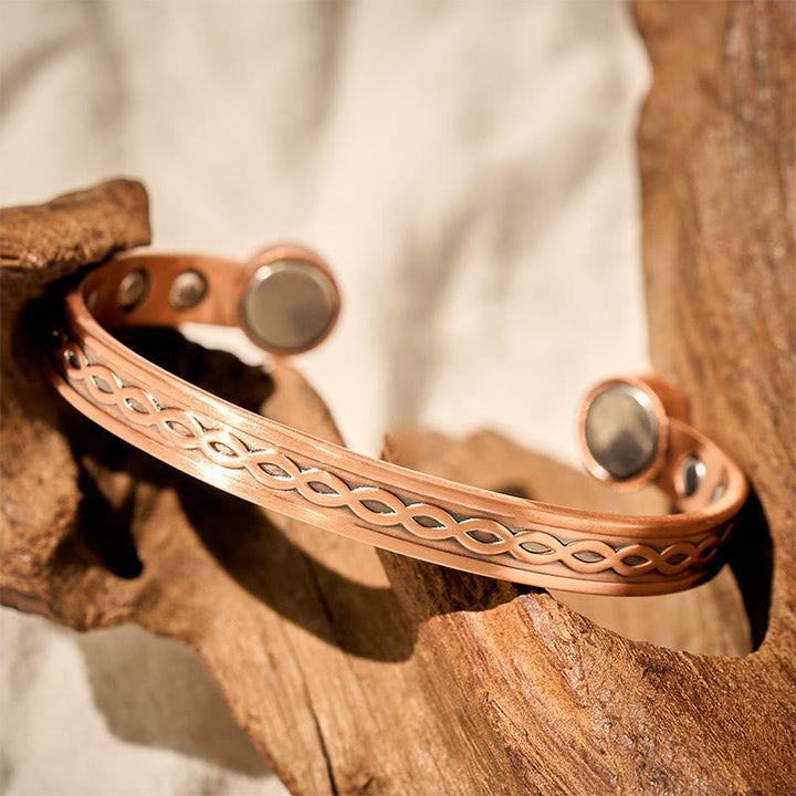 Kupfer Armband mit Flechtmuster und Magneten auf Holz Glück Balance Segen