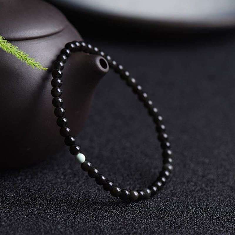 Armband Schwarzer Obsidian Türkis – Stärke neben Teekanne mit grünem Zweig
