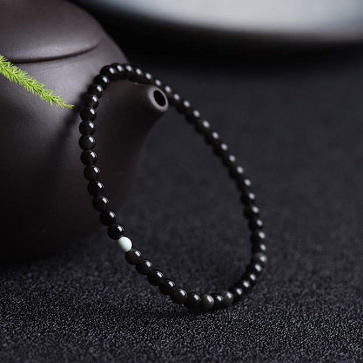 Armband Schwarzer Obsidian Türkis – Stärke neben Teekanne mit grünem Zweig