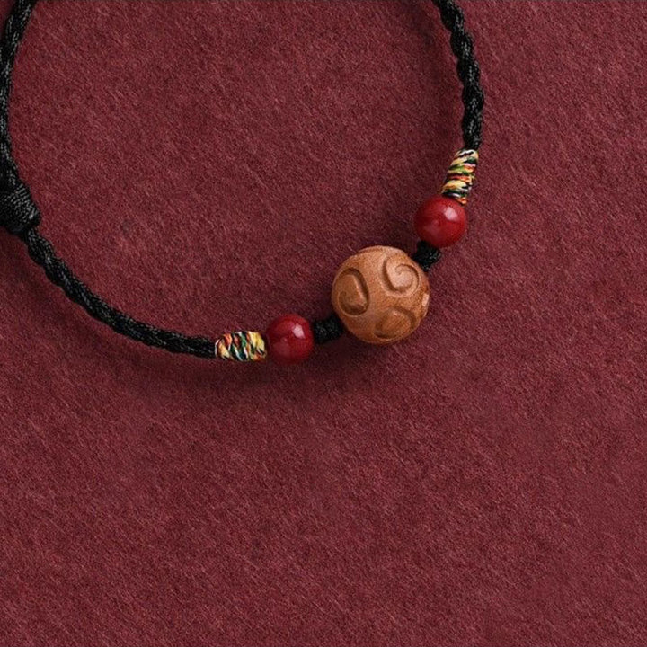 Armband Pfirsichholz Zinnober Glück geflochten schwarz rote Perlen Handgelenk