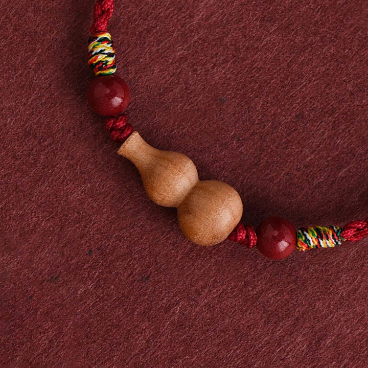 Armband Pfirsichholz Glück Wohlstand Kalebasse Anhänger rotes geflochtenes Seil Detail