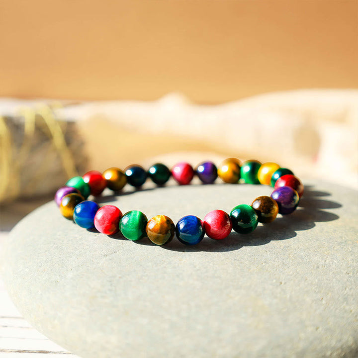 Buntes Tigerauge Armband mit Natursteinen auf Stein Oberfläche.