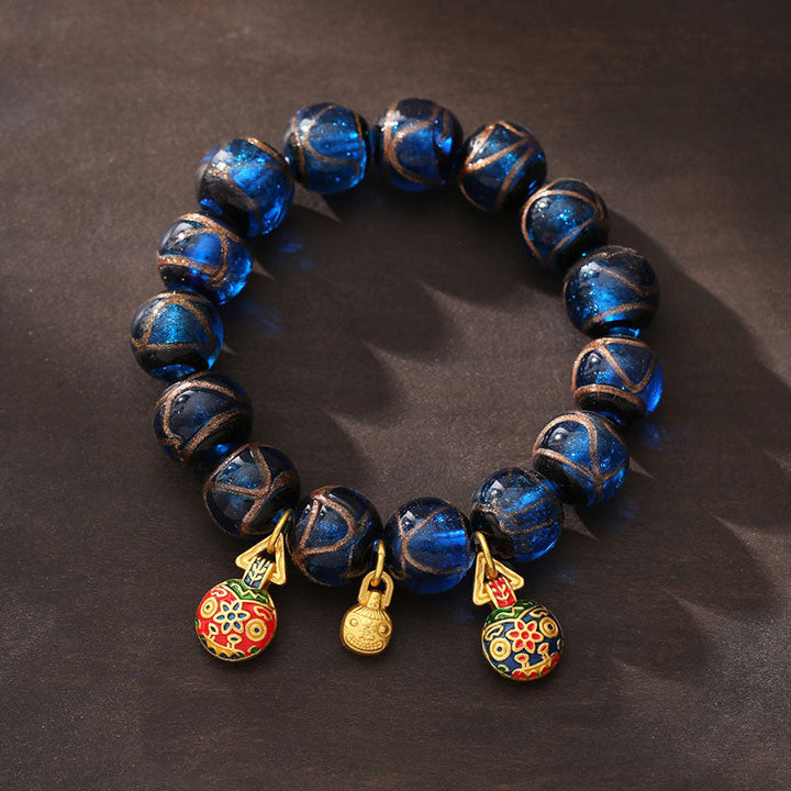 Armband mit blauen Perlen und vergoldeten Glücksbringern Anhängern