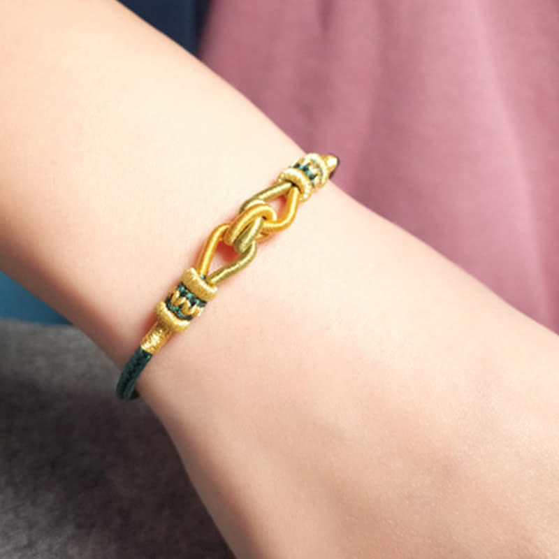 Goldenes Armband mit Knoten-Design am Handgelenk getragen elastisch geflochten.