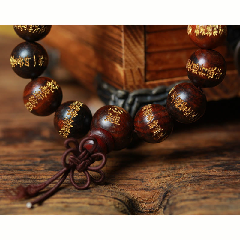 Armband Rosenholz Herzsutra mit Goldverzierung auf Holztisch.