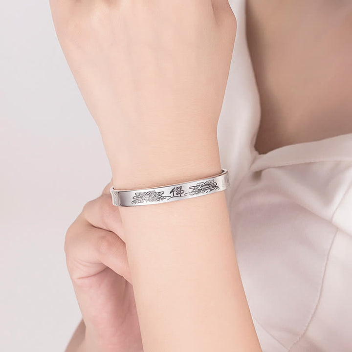 Silbernes Armband mit Herzsutra-Gravur am Handgelenk getragen.