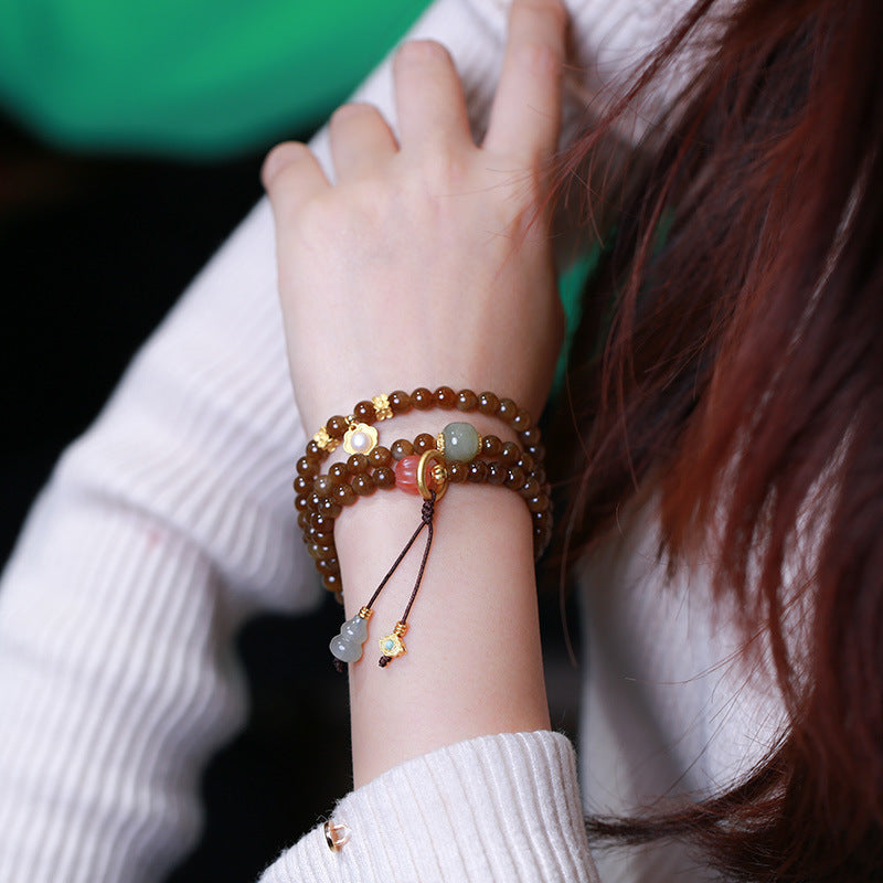 Jade Schmetterling Armband mit braunen Perlen elegant am Handgelenk getragen.