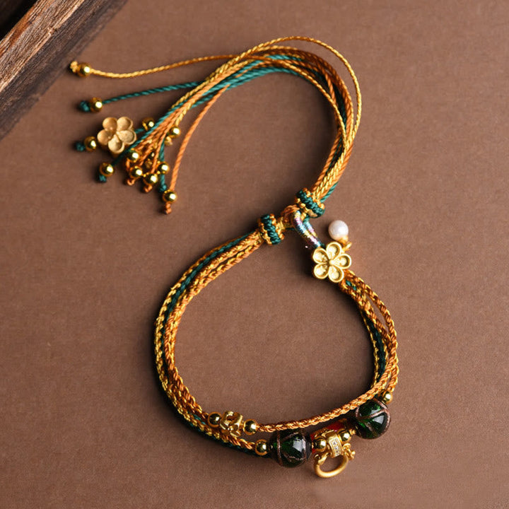 Armband – Heilung & Stärke mit goldenen Fäden und grünen Perlen.