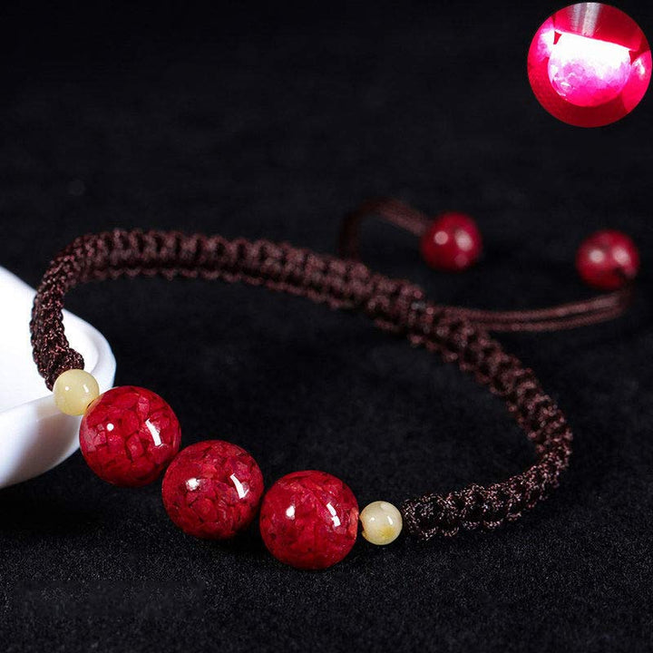 Armband Zinnober – Segen mit roten Perlen auf schwarzem Hintergrund