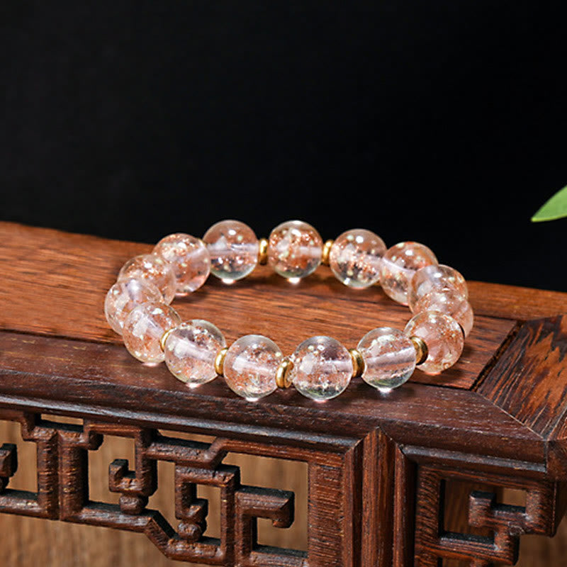 Roségold Kristall Armband mit goldenen Perlkappen auf Holzoberfläche.