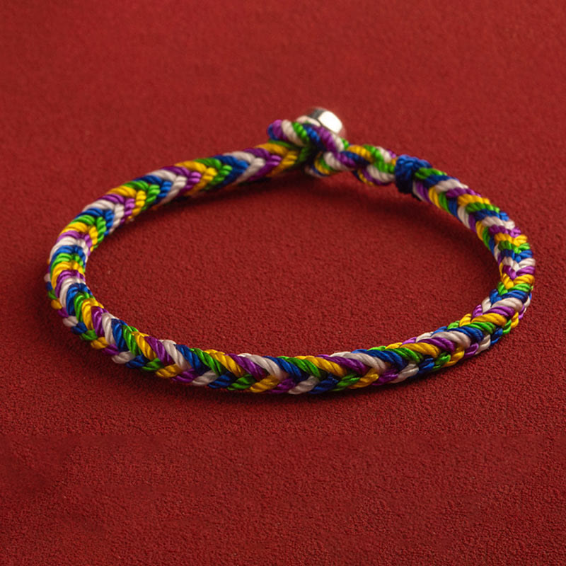 Buntes geflochtenes Armband mit Glück Symbol auf rotem Hintergrund.