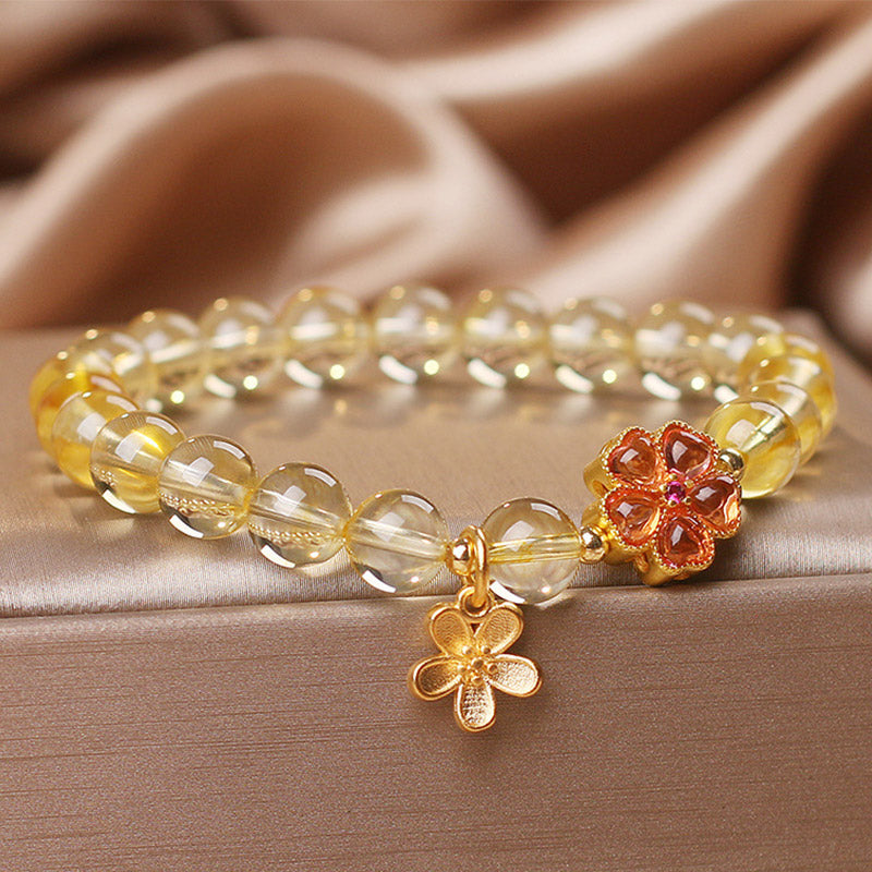 Armband Citrin mit goldenen Blütenanhängern am Handgelenk getragen