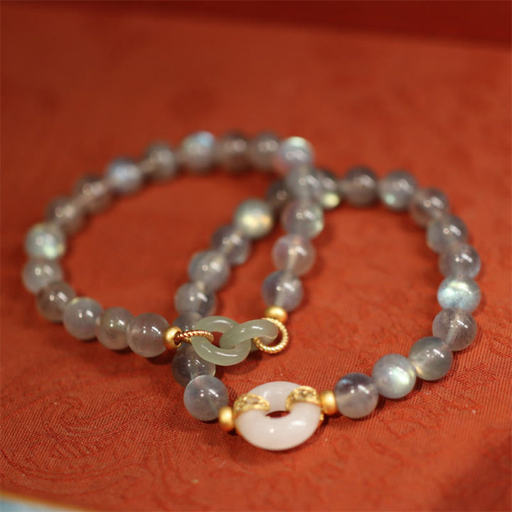Mondstein Jade Armband mit goldenem Verschluss auf rotem Stoff elegante Gestaltung