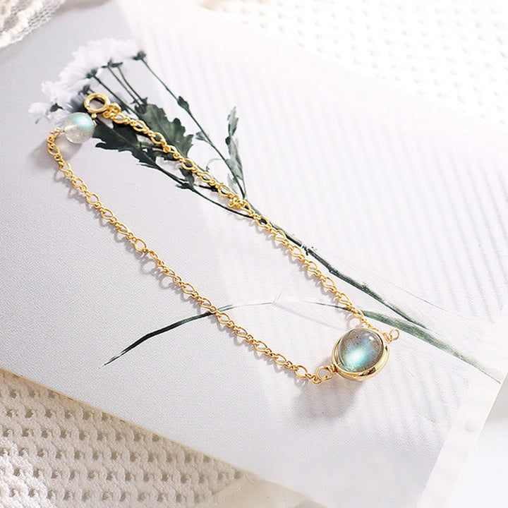 Goldenes Armband Mondstein mit weißen Blüten elegant arrangiert.