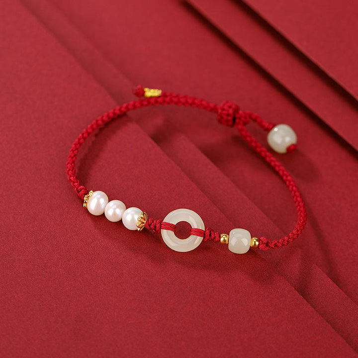 Rotes Armband mit Perlen und goldenen Akzenten elegant präsentiert.