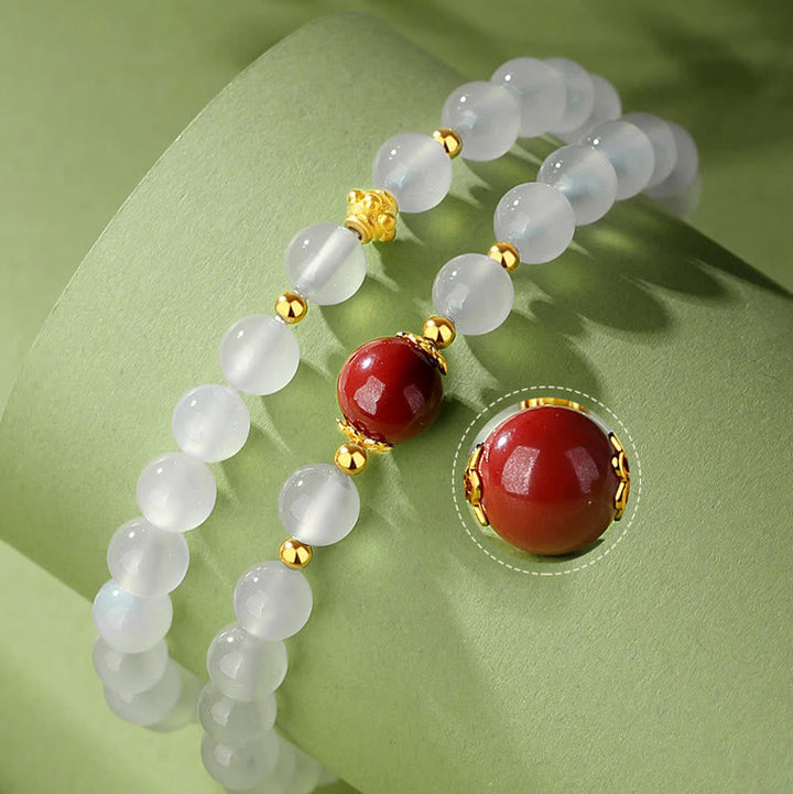 Weißes Jade Armband mit roten Zinnober Perlen und Gold-Elementen.