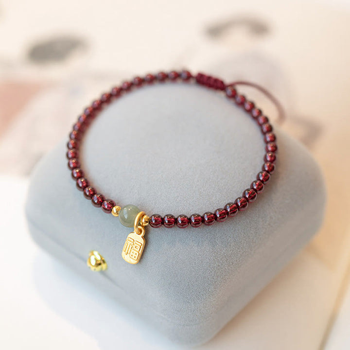 Armband Erdbeerquarz Granat Fu-Zeichen Glück Heilung auf grauem Stein