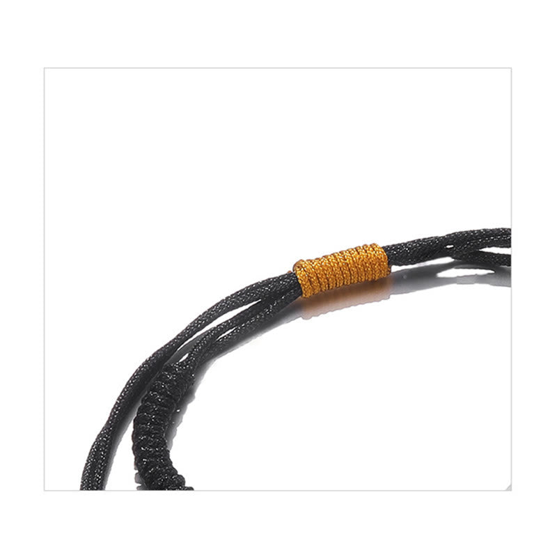 Schwarzes geflochtenes Armband mit goldenem Wickel Detail.