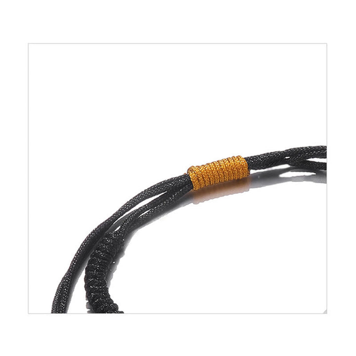 Schwarzes geflochtenes Armband mit goldenem Wickel Detail.