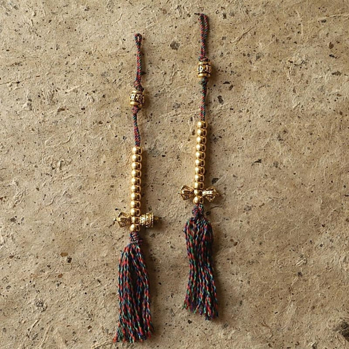 Mala Bodhi Wohlstand Energie Armband mit goldfarbenen Perlen und Quaste.