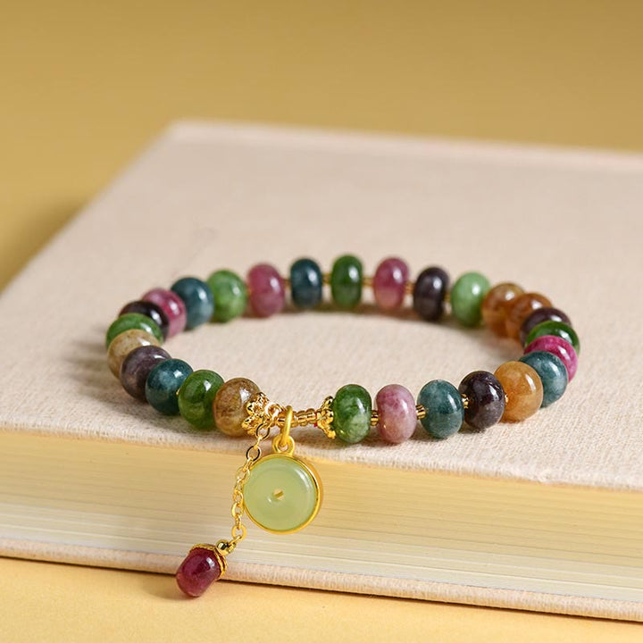 Buntes Turmalin Armband mit Anhänger auf cremefarbenem Untergrund.