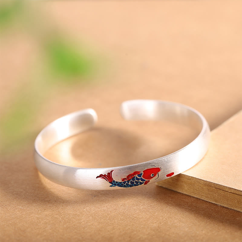 Silbernes Armband mit rotem Koi Fisch Design auf Holzoberfläche.