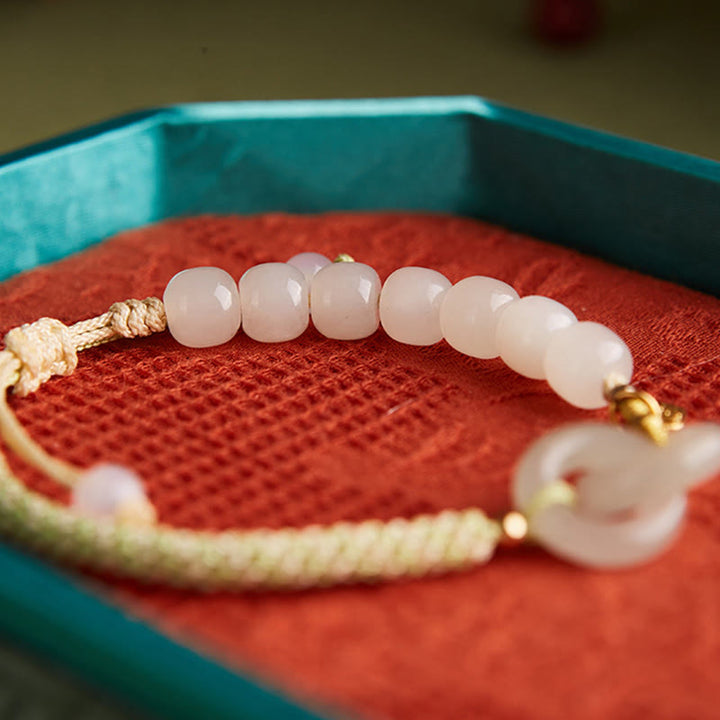 Jade Armband mit Perlen und goldenem Verschluss auf rotem Stoff.