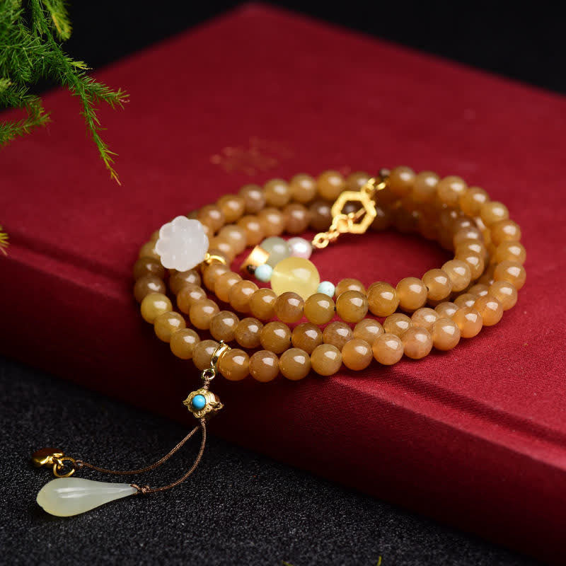 Armband mit bernsteinfarbenen Perlen und weißer Jade Lotus Anhänger.