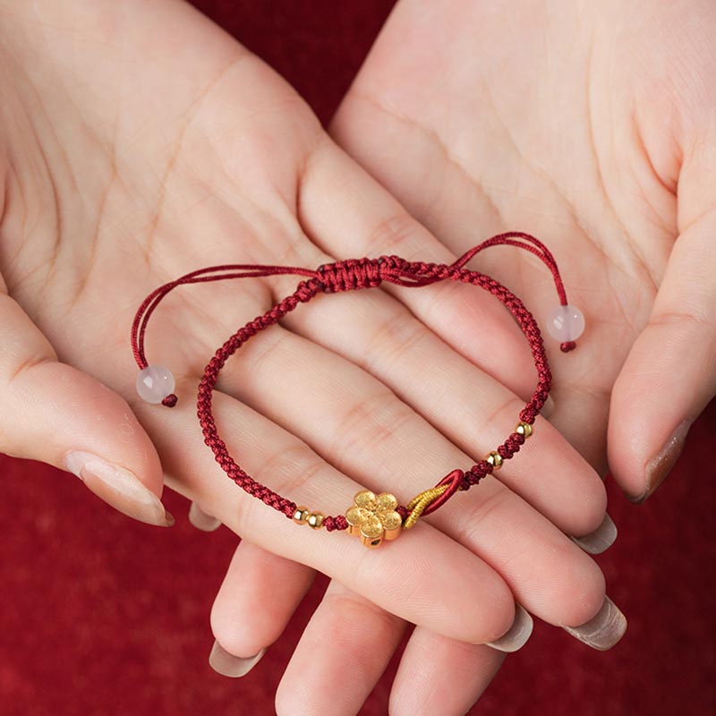 Rotes Armband mit goldenem Glücksbringer elastisch getragen Handgelenk