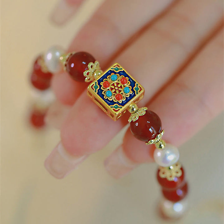 Armband Roter Achat Perle mit vergoldetem Emaille Zentrum am Handgelenk.