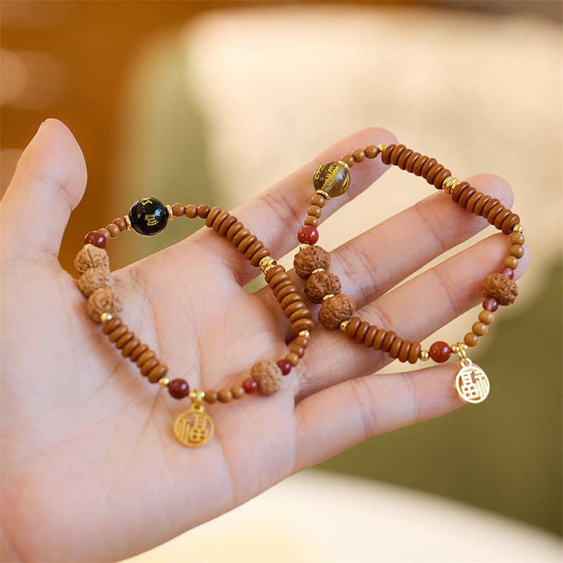 Zwei Armbänder mit Bodhi-Perlen und goldenen Charms am Handgelenk getragen.