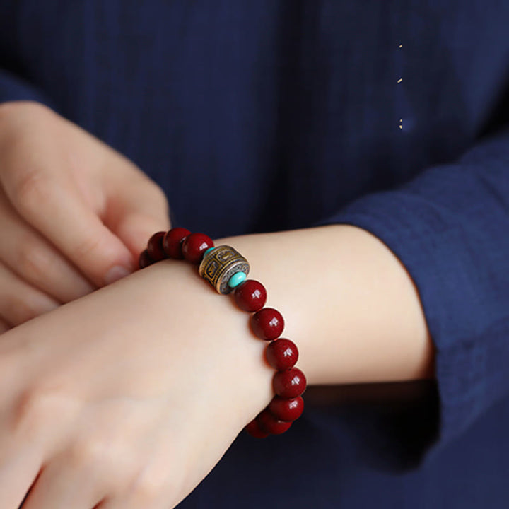 Rotes Armband mit Om Mani Padme Hum Anhänger am Handgelenk getragen