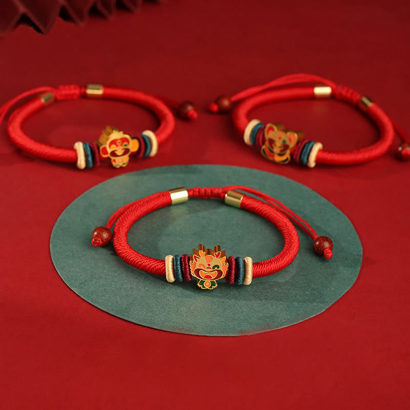 Rotes Seidenarmband mit goldenem Löwenkopf Charm, elastisch tragbar.