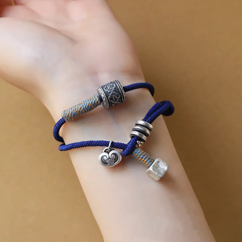 Blaues doppelgeflochtenes Armband Om Mani Padme Hum mit Charms am Handgelenk.