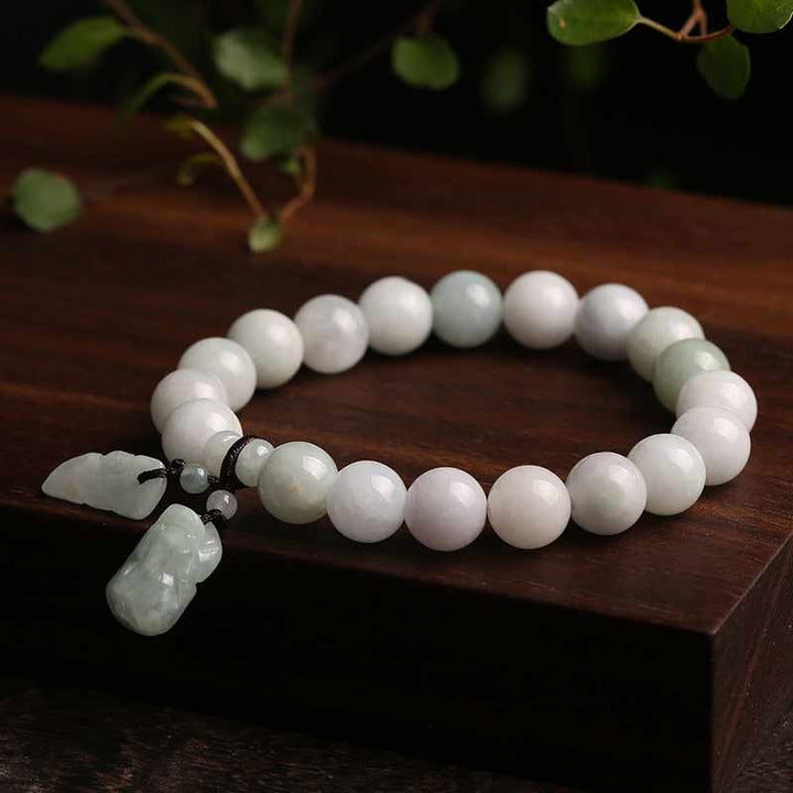 Weißes Jade Pixiu Armband mit Anhänger auf Holzoberfläche.