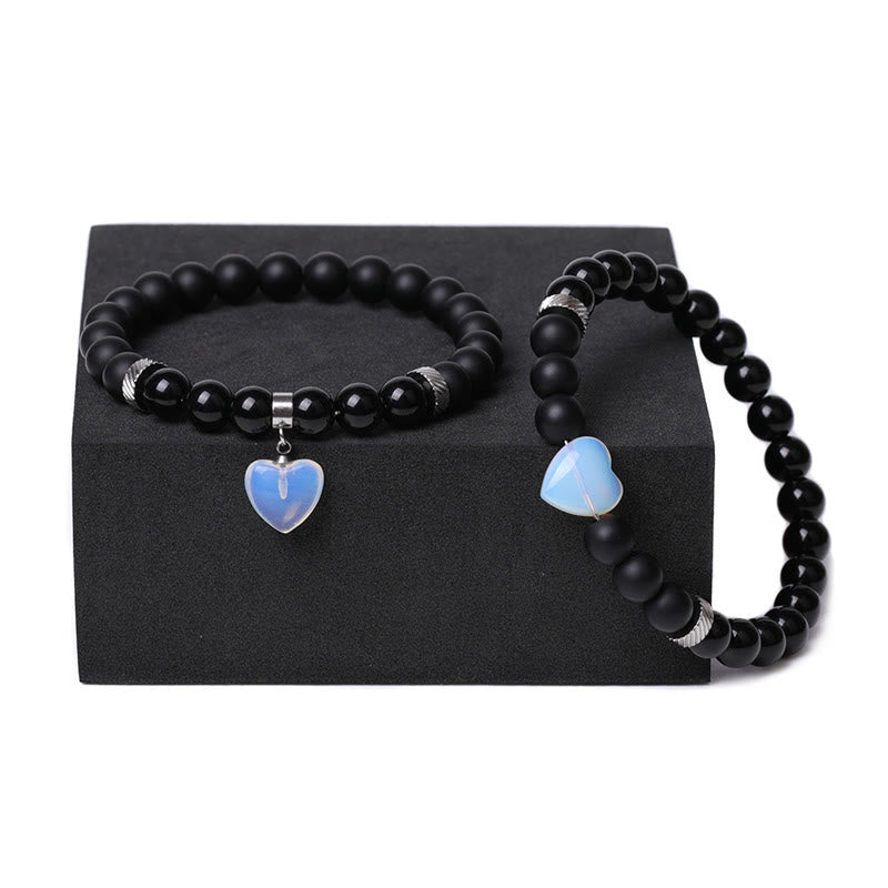 Armband Schwarzer Onyx Kristall Paar mit blauen Herzanhängern displayed.