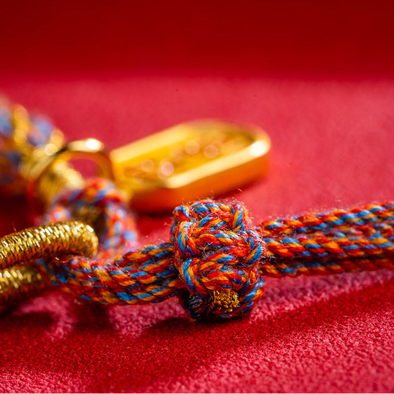 Armband Om Mani Padme Hum Multicolored mit goldenen Elementen auf rotem Hintergrund.