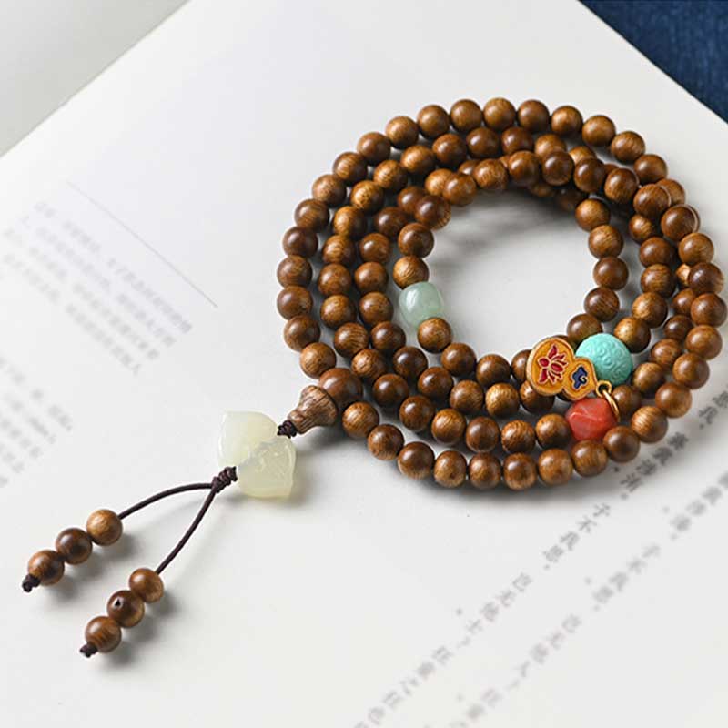 Mala Rosenholz Armband mit Jade und Koralle auf Papier.