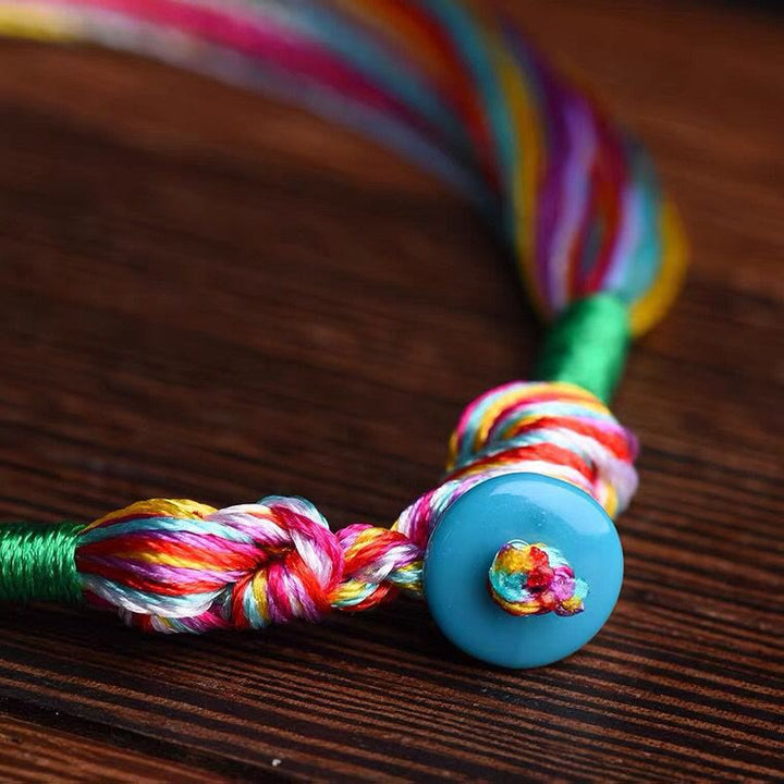 Buntes Fünffarben Armband mit blauer Perle auf Holzoberfläche Schutz.
