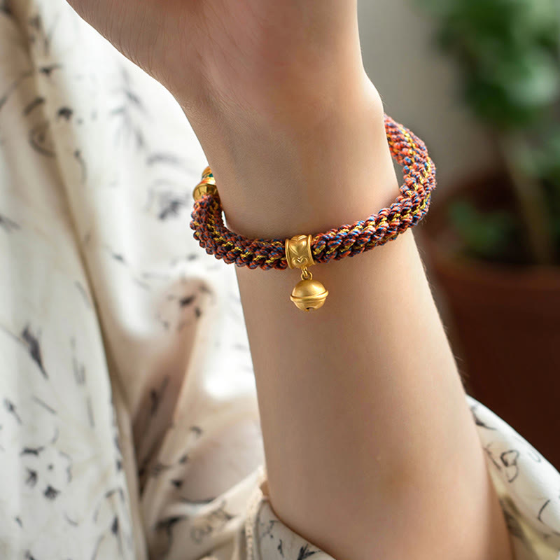 Geflochtenes Armband mit goldenem Om Anhänger am Handgelenk getragen.