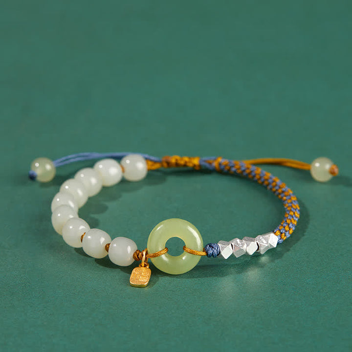 Jade Armband mit weißen Perlen und Silber Elementen grünem Hintergrund.