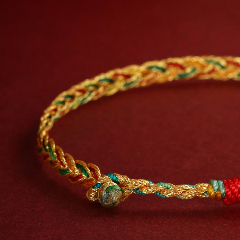 Goldenes Drachen-Armband mit roten und grünen Fäden elastisch getragen