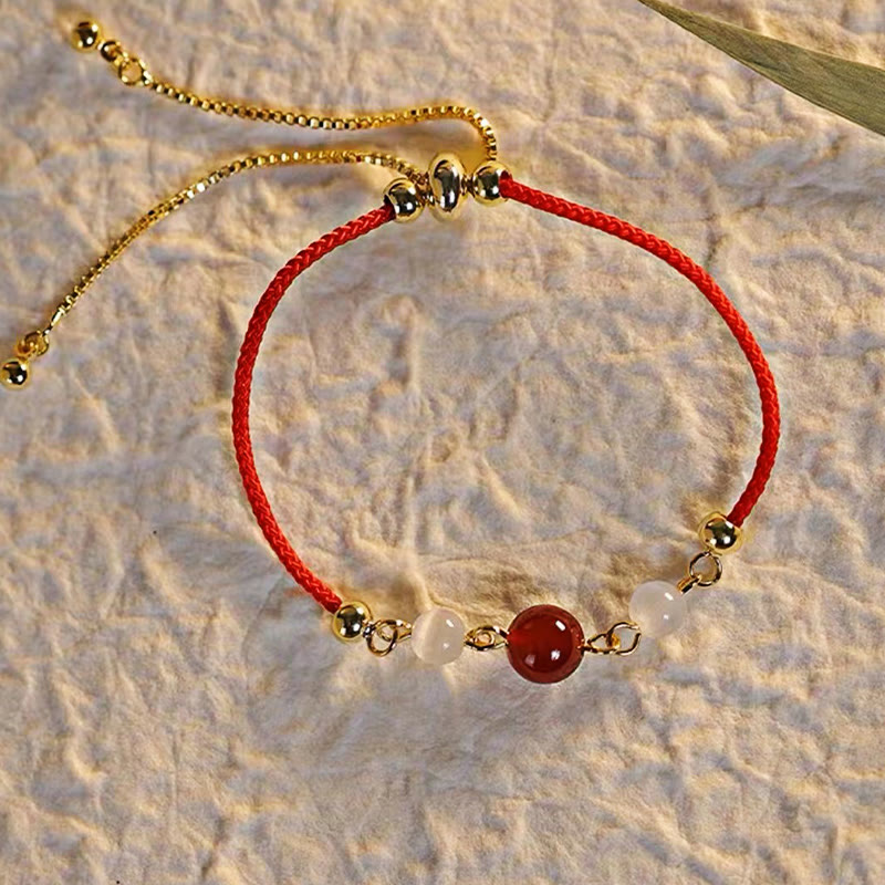 Rotes Achat Armband mit goldenem Verschluss auf Sand elegant.