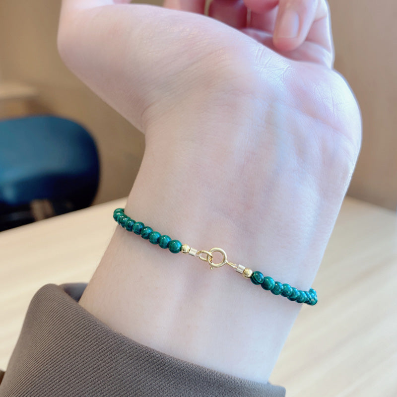 Grünes Malachit Armband mit Golddetails am Handgelenk getragen.