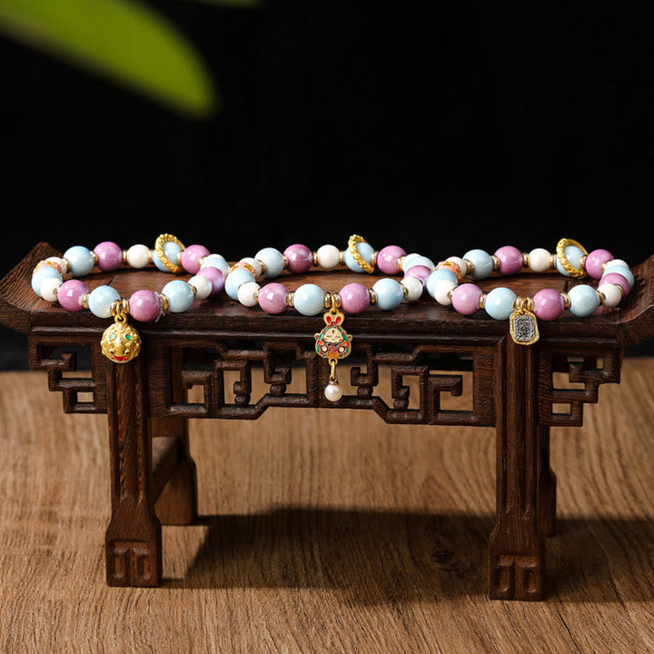 Armband – Schutz & Wohlstand & Energie, Perlen rosa weiß blau gold Anhänger Holzständer