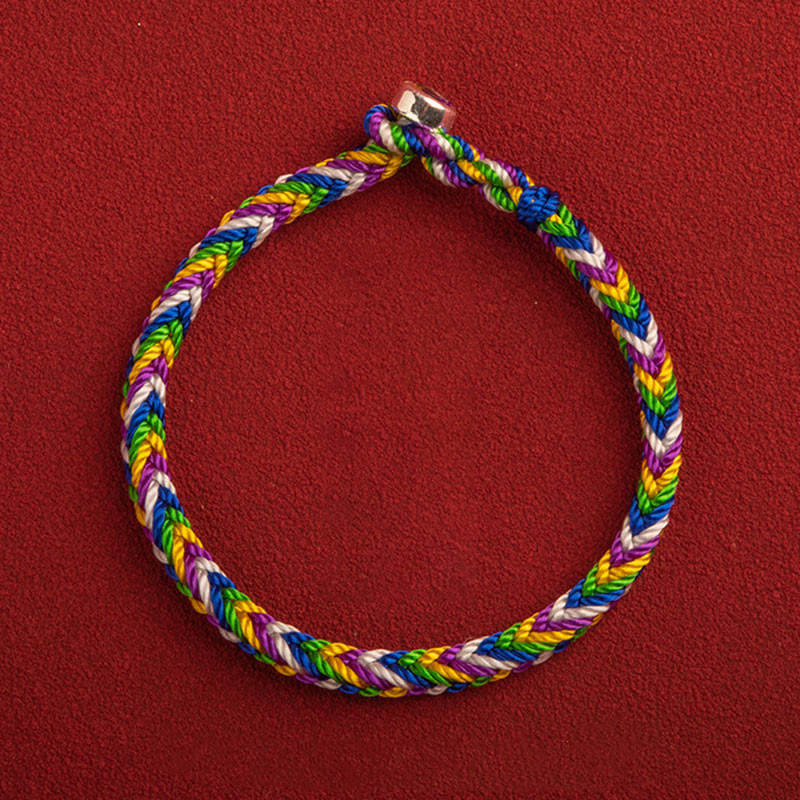 Buntes geflochtenes Armband mit Glück Charm auf rotem Hintergrund.