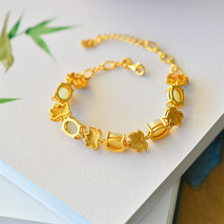 Goldenes Lotus Armband mit eleganten Perlen auf weißem Hintergrund.