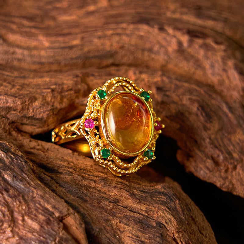 Ring Bernstein Blume Goldoptik grüne Steine Edelstein Schmuck Holzhintergrund
