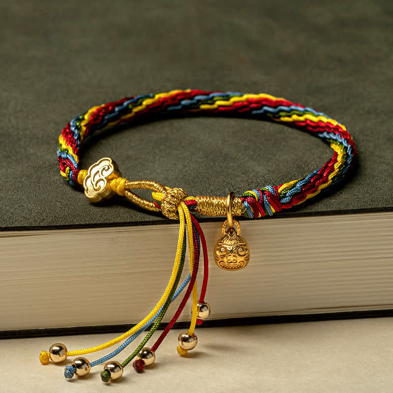 Buntes Armband mit Goldelementen und Glücksbringer Anhängern auf Buch.