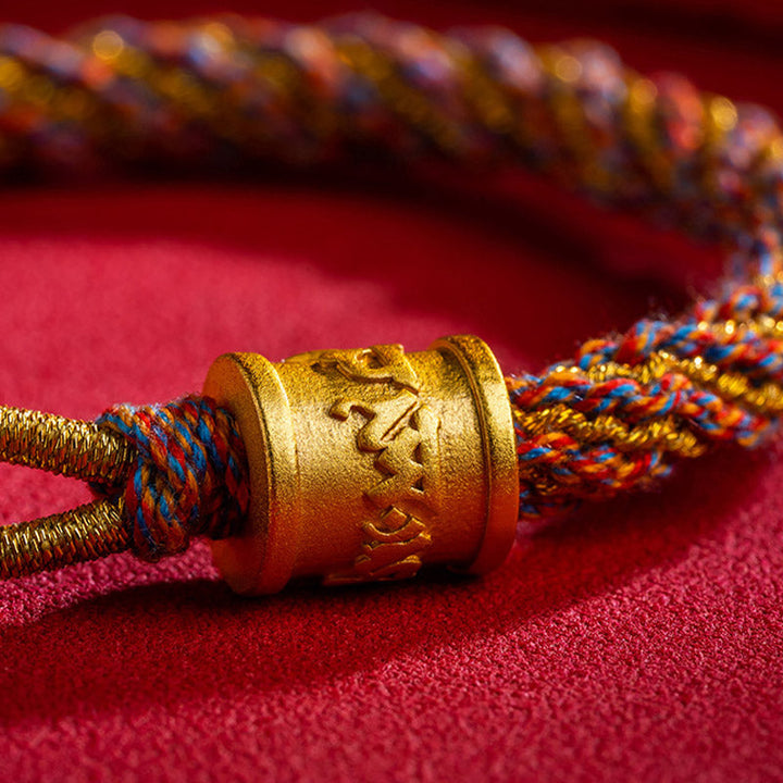 Armband Om Mani Padme Hum Multicolored mit goldenem Verschluss auf rotem Stoff.